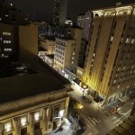 Night view from above of a busy city street with illuminated historic buildings.