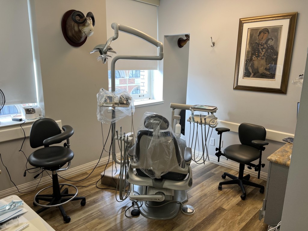 A second dental operatory room with specialized lighting, a patient chair, and stools.