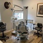 A second dental operatory room with specialized lighting, a patient chair, and stools.