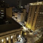 Night view from above of a busy city street with illuminated historic buildings.